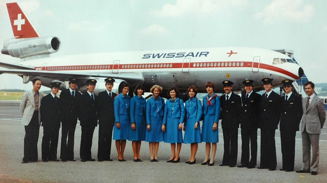 Eine Gruppe uniformierter Männer und Frauen vor einem Flugzeug. Eine Gruppe uniformierter Männer und Frauen vor einem Flugzeug.