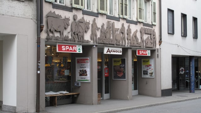 Ein verziertes Haus, im Erdgeschoss ein Lebensmittelladen. Ein verziertes Haus, im Erdgeschoss ein Lebensmittelladen.