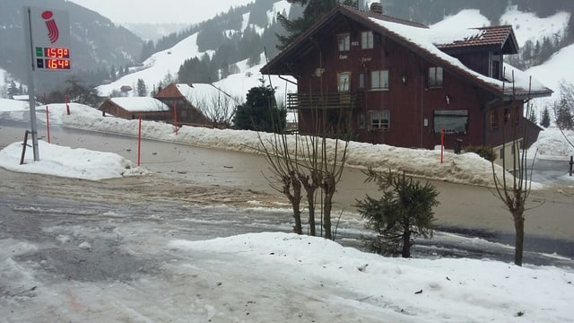 Strasse und Parkplatz in Jaun mit stehendem Wasser Strasse und Parkplatz in Jaun mit stehendem Wasser