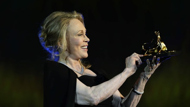 Frau hält eine Leoparden Skulptur in der Hand und schaut sie an. Frau hält eine Leoparden Skulptur in der Hand und schaut sie an.