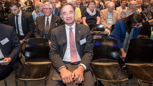 Mann sitzt in der ersten Reihe einer Versammlung Mann sitzt in der ersten Reihe einer Versammlung