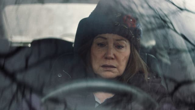 Eine Frau mit traurigem Gesicht sitzt in Winterkleidung im Auto. Eine Frau mit traurigem Gesicht sitzt in Winterkleidung im Auto.