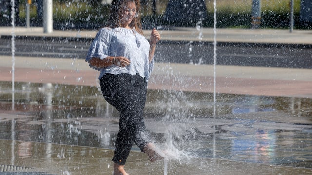 Frau kühlt Füsse in Wasserstrahl ab Frau kühlt Füsse in Wasserstrahl ab