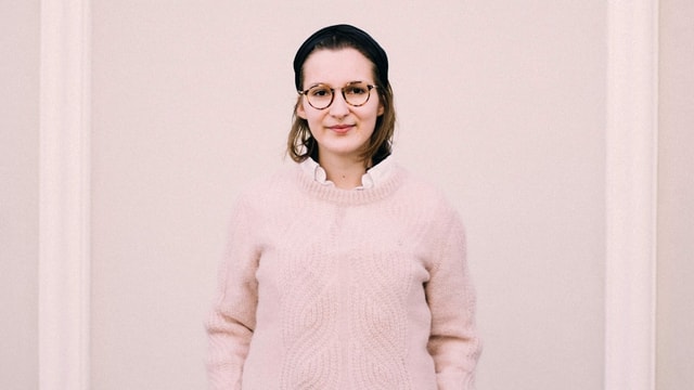 Frau mit Brille steht vor einer Wand. Frau mit Brille steht vor einer Wand.