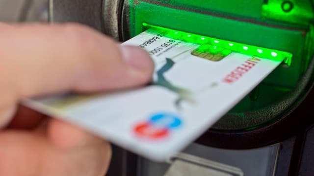 Bankkarte wird in einen Automatenschlitz geschoben. Bankkarte wird in einen Automatenschlitz geschoben.