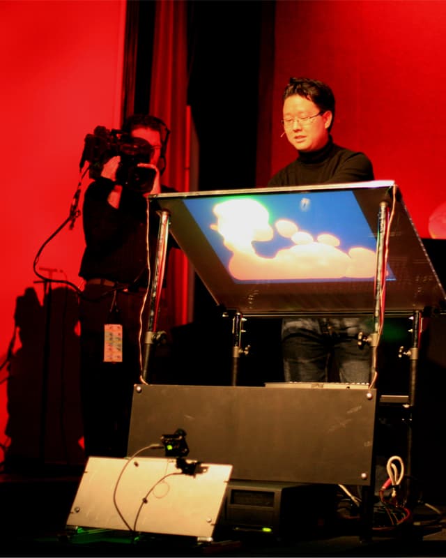 Asiatisch stämmiger Mann vor dem Prototypen eines Touchscreens. Asiatisch stämmiger Mann vor dem Prototypen eines Touchscreens.