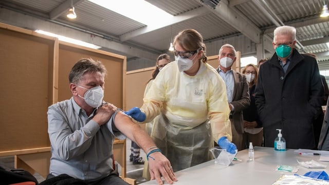 Mann mit Maske lässt sich impfen Mann mit Maske lässt sich impfen
