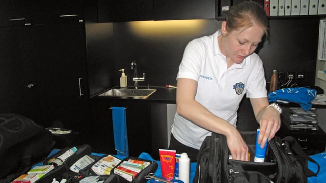 Eine junge Frau - eine Physiotherapeutin - beim Packen einer Tasche mit medizinischen Utensilien. Eine junge Frau - eine Physiotherapeutin - beim Packen einer Tasche mit medizinischen Utensilien.