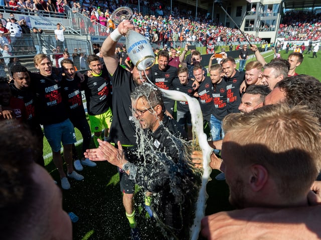 Michael Köllner wird vor der Aufsteigermannschaft mit Bier geduscht.