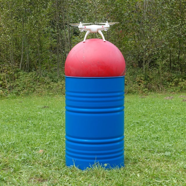 Eine Drohne auf einem Gymnastikball auf einem Fass auf einer Wiese. Eine Drohne auf einem Gymnastikball auf einem Fass auf einer Wiese.
