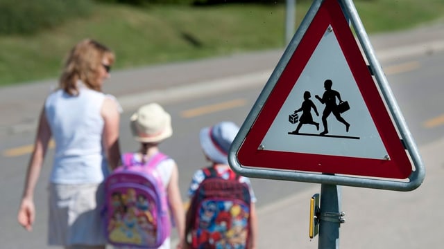 Kinder und ihre Mutter auf dem Schulweg. Kinder und ihre Mutter auf dem Schulweg.