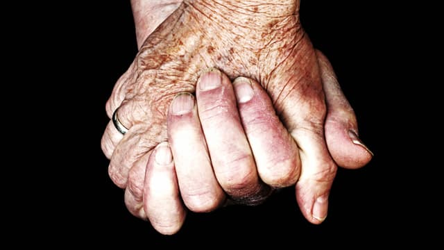 Zwei Hände, die sich halten. Die Hand eines Erwachsenen und die einer sehr alten Person / Symbolbild
