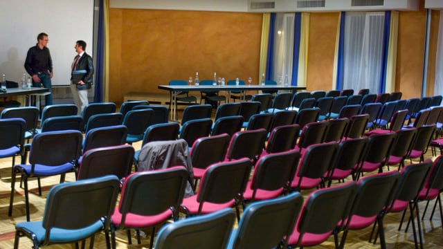 Leere Stühle in einem vollen Saal Leere Stühle in einem vollen Saal