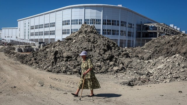 Eine Dame läuft bei einer Baustelle vorbei Eine Dame läuft bei einer Baustelle vorbei