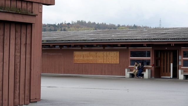 Zwei Personen vor dem Gabäude aus Holz. Zwei Personen vor dem Gabäude aus Holz.