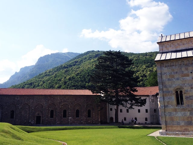 Klostergebäude unter strahlend blauem Himmel vor waldigem Hügel. Klostergebäude unter strahlend blauem Himmel vor waldigem Hügel.
