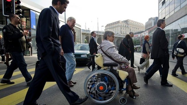 Eine Frau im Rollstuhl überquert die Strasse Eine Frau im Rollstuhl überquert die Strasse