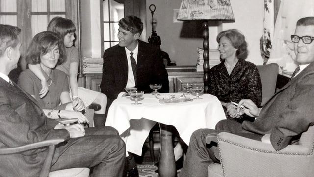 Eine Familie sitzt um ein Sofatischchen, auf dem Champagner-Gläser stehen. Eine Familie sitzt um ein Sofatischchen, auf dem Champagner-Gläser stehen.