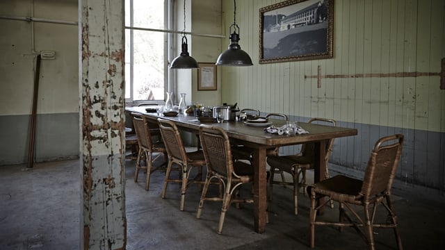 Mittagstisch Fabrik: Ein Tisch mit mehreren Stühlen in einem alten hohen Raum. Mittagstisch Fabrik: Ein Tisch mit mehreren Stühlen in einem alten hohen Raum.