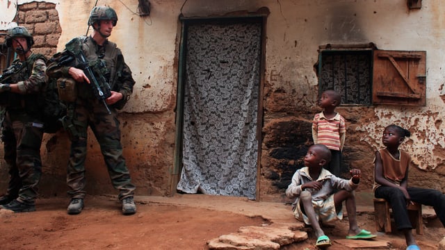 Soldaten mit Gewehr vor Kindern