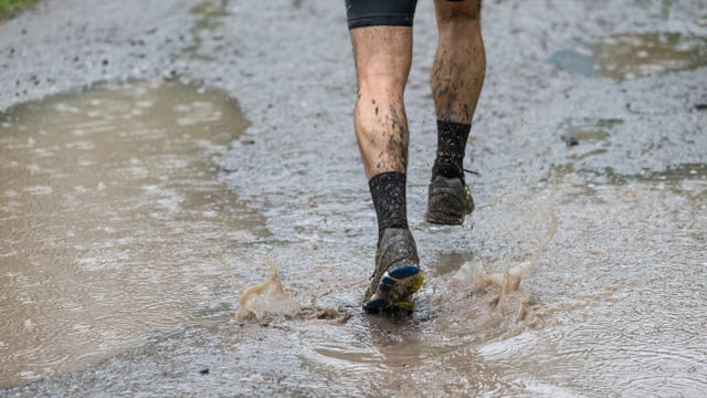 Ein Läufer passiert eine Wasserlache bei Filisur im Albulata. Der Grund: Dauerregen am 29. Swiss Alpine Marathon über 78.5 Kilometer