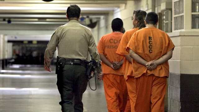 Ein Gefängniswächter eskortiert US-Gefangene. Ein Gefängniswächter eskortiert US-Gefangene.