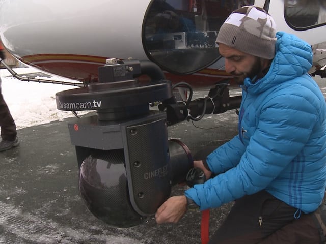 Ein Kameramann montiert eine Cineflex-Kamera an einen Helikopter. Ein Kameramann montiert eine Cineflex-Kamera an einen Helikopter.