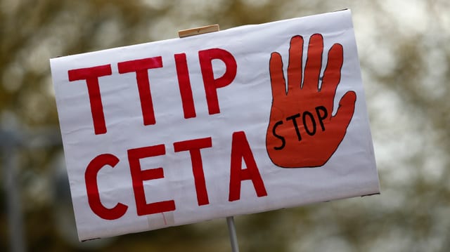 Schild eines Demonstranten mit TTIP und Ceta als Schriftzug und einer Stop-Hand.