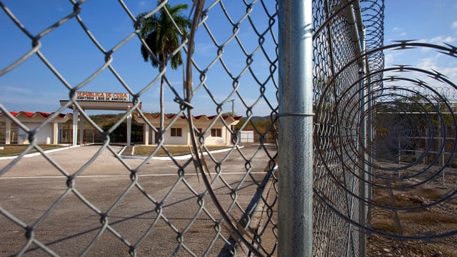 Blick durch hohen Zaun und Stacheldraht ins Gefaengnis Guantanamo Blick durch hohen Zaun und Stacheldraht ins Gefaengnis Guantanamo