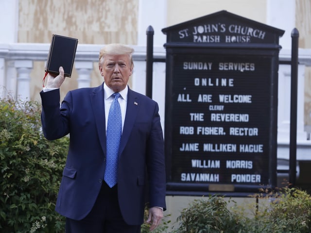 Präsident Trump steht vor einer Kirche mit Bibel in der Hand.