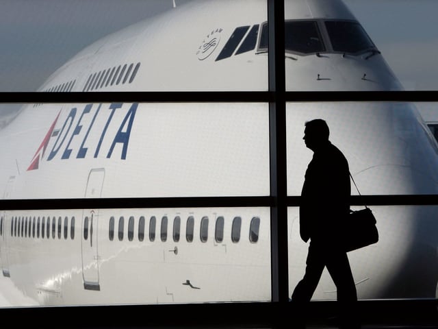 Ein Mann geht an einem Flughafen vor einer 747 durch. Ein Mann geht an einem Flughafen vor einer 747 durch.