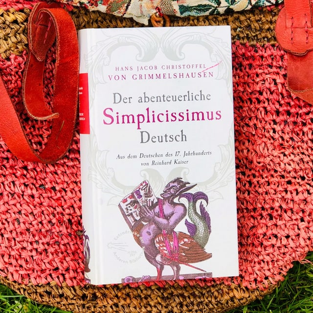 Der Schelmenroman «Der abenteuerliche Simplicissimus Deusch» von Hans Jacob Christoffel von Grimmelshausen liegt auf einer Beuteltasche Der Schelmenroman «Der abenteuerliche Simplicissimus Deusch» von Hans Jacob Christoffel von Grimmelshausen liegt auf einer Beuteltasche