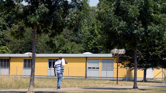 Mann geht auf Bundesasylzentrum Embrach (Gelbe Baracke) zu. Mann geht auf Bundesasylzentrum Embrach (Gelbe Baracke) zu.