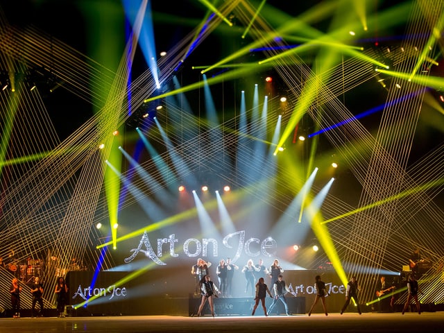 Sänger und Tänzer auf der Bühne mit Lichtshow.