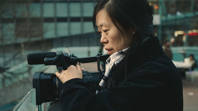 Eine Frau filmt mit einer Kamera.