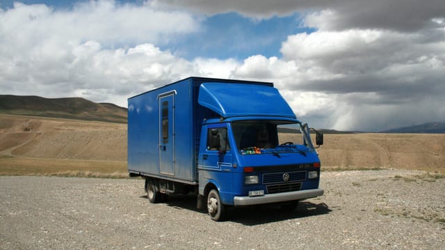 Ein blauer, umgebauter VW-Bus vor hügeliger Landschaft. Ein blauer, umgebauter VW-Bus vor hügeliger Landschaft.