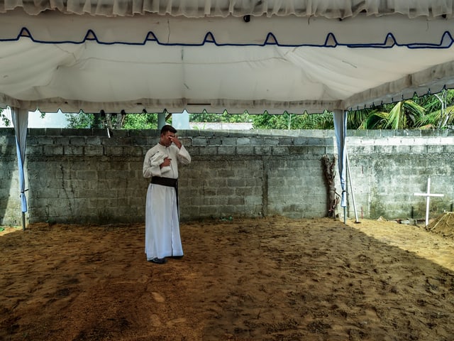 Ein erschöpfter Priester bei einer Pause zwischen Beerdigungen Ein erschöpfter Priester bei einer Pause zwischen Beerdigungen