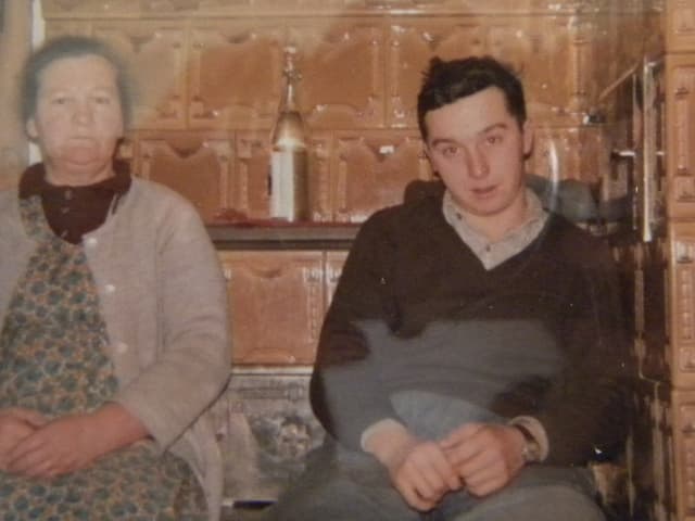Mutter und Sohn sitzen auf der Ofenbank eines Bauernhauses. Mutter und Sohn sitzen auf der Ofenbank eines Bauernhauses.