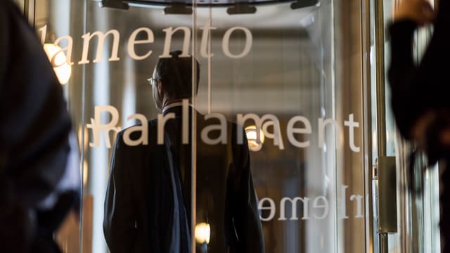 Eine Drehtüre aus Glas mit der Aufschrift Parlament. Eine Drehtüre aus Glas mit der Aufschrift Parlament.