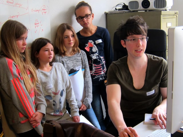 Ein Mann am Computer erklärt vier Mädchen etwas.