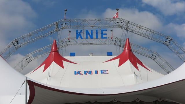 Rundbogen aus Metall mit Knie-Schriftzug über dem Zirkuszelt Rundbogen aus Metall mit Knie-Schriftzug über dem Zirkuszelt