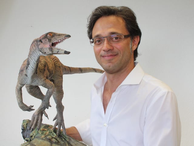 Ein Mann mit brille, davor das Modell eines Dinosauriers. Ein Mann mit brille, davor das Modell eines Dinosauriers.