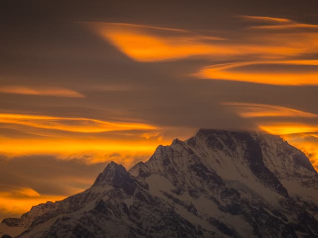 Verschneiter Berg und gelbliche Wolken.