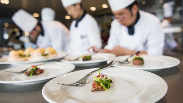 Köche bereiten exklusive Mahlzeit (Häppchen) auf Tellern in der Küche zu Köche bereiten exklusive Mahlzeit (Häppchen) auf Tellern in der Küche zu