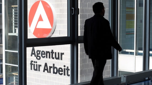 Mann im Gegenlicht in einem Bürogebäude, auf einer Aussenmauer steht: "Agentur für Arbeit" Mann im Gegenlicht in einem Bürogebäude, auf einer Aussenmauer steht: "Agentur für Arbeit"