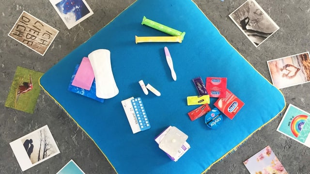 Auf einem kissen liegen Kondome, ein Schwangerschaftstest, Binden, Tampons und Pillen. Auf einem kissen liegen Kondome, ein Schwangerschaftstest, Binden, Tampons und Pillen.