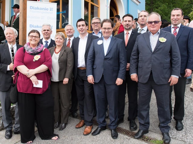 Eine Gruppe Menschen steht vor einem Haus. Eine Gruppe Menschen steht vor einem Haus.