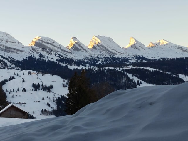 Churfirsten im Schnee werden besonnt von den ersten Sonnenstrahlen.