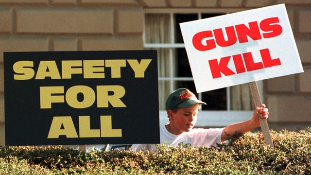 Ein Junge stellt anti-Waffen Schilder auf