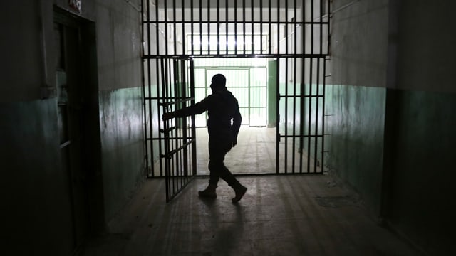 Wachperson öffnet Gefängnistür Wachperson öffnet Gefängnistür